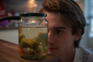 person looking closely to a jar of ferment